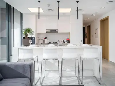 a kitchen with white cabinets and a bar with stools at Stylish JVC 1 Bed with Wraparound Balcony in Dubai