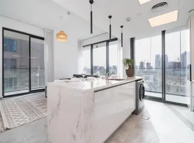 a kitchen with white counters and large windows at Stylish JVC 1 Bed with Wraparound Balcony in Dubai