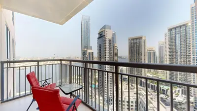 a red chair on a balcony with a view of the city at Creek Residences - One Bedroom with Creek View in Dubai