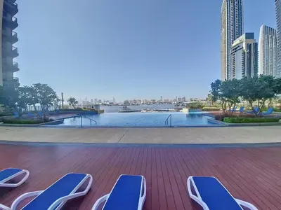 a deck with lounge chairs and a view of a river at Creek Residences - One Bedroom with Creek View in Dubai