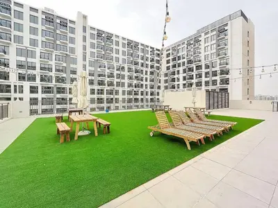 a group of benches sitting on a green lawn in front of a building at UNA Tower - Peaceful One Bedroom in Townsquare in Dubai