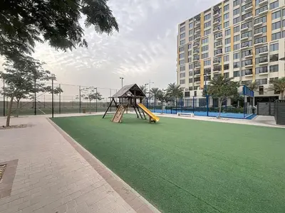 a playground with a slide on a green field at UNA Tower - Peaceful One Bedroom in Townsquare in Dubai