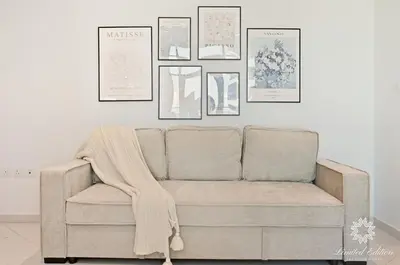 a couch in a living room with pictures on the wall at Seven Palm Residences - Private Beach Access, Infinity Pool with Sea View in Dubai