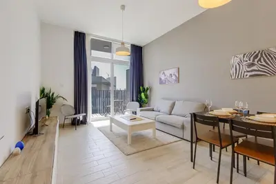 a living room with a couch and a table at Stylish 2BR Apartment in Belgravia III A, JVC - Allsopp & Allsopp in Dubai