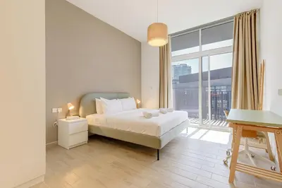 a bedroom with a bed and a large window at Stylish 2BR Apartment in Belgravia III A, JVC - Allsopp & Allsopp in Dubai