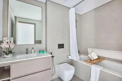 a bathroom with a tub and a toilet and a sink at Frank Porter - Grande Signature Residence in Dubai