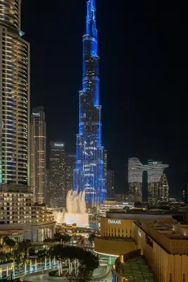 a tall skyscraper lit up in blue at night at Trendy 1BR Dubai Dream with full BurjViews Above Dubai Mall in Dubai