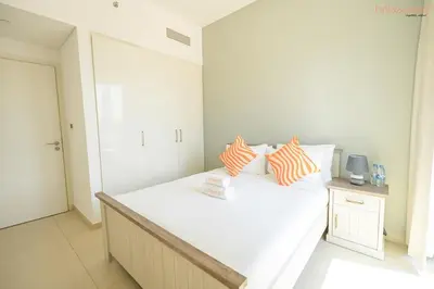 a bedroom with a white bed with orange and white pillows at Bnbeyond's Artistic Luxe Retreat with Burj Views in Dubai