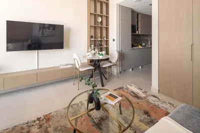 a living room with a glass table and a tv at Frank Porter - Westwood Grande in Dubai