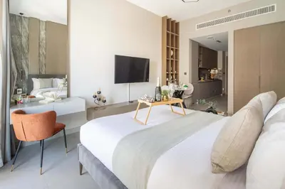 a bedroom with a bed and a table and a tv at Frank Porter - Westwood Grande in Dubai