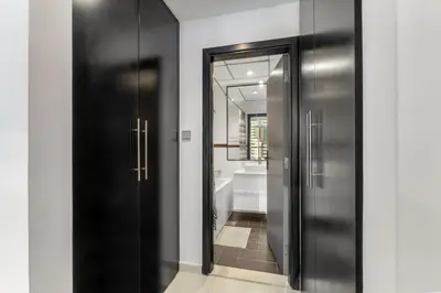 a hallway with two black doors and a bathroom at Modern 1BR JBR View No Car Needed! in Dubai