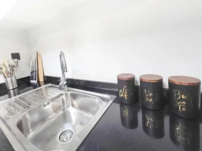a kitchen counter with a sink and two cups at Daraqa - Modern 1BR Apartment in Peaceful Dubai Land in Dubai