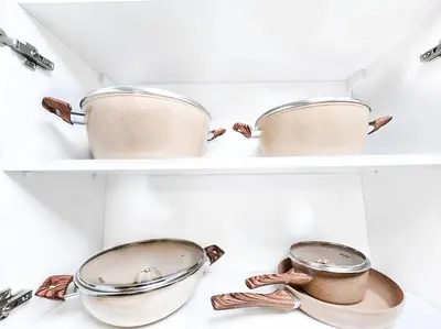 two shelves with pots and pans in a kitchen at Daraqa - Modern 1BR Apartment in Peaceful Dubai Land in Dubai