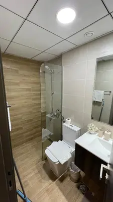 a bathroom with a toilet and a shower and a sink at Daraqa - Modern 1BR Apartment in Peaceful Dubai Land in Dubai