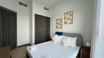 a bedroom with a bed with white sheets and pillows at Daraqa - Modern 1BR Apartment in Peaceful Dubai Land in Dubai