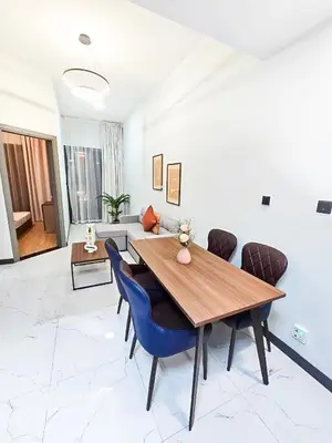 a dining room with a wooden table and blue chairs at Daraqa - Modern 1BR Apartment in Peaceful Dubai Land in Dubai