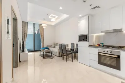 a kitchen and living room with a couch and a table at Chic One-Bed Haven w Pool & Gym Heart of Dubai in Dubai