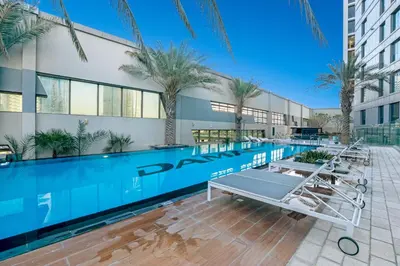 a swimming pool in front of a building with palm trees at Live the Dubai Dream Premium Flat in Business Bay in Dubai