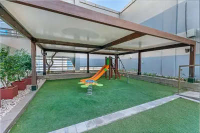 an outdoor play area with a slide on a green lawn at Live the Dubai Dream Premium Flat in Business Bay in Dubai