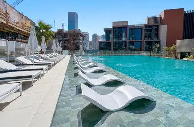 a large swimming pool with white lounge chairs on a building at Modern 1Bedroom w Burj Khalifa view in Peninsula in Dubai