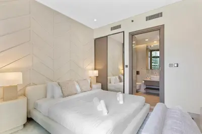a white bedroom with a large white bed and a mirror at Modern 1Bedroom w Burj Khalifa view in Peninsula in Dubai
