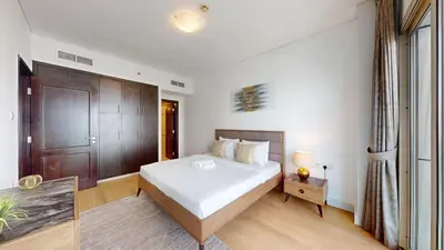 a bedroom with a white bed and a wooden door at Royal Oceanic - Bright Two Bed on the 14th Floor in Dubai