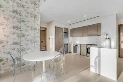 a white kitchen with a white table and chairs at Skyline View, Stay High Rise Luxury next to Burj in Dubai