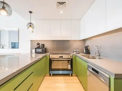 a kitchen with green and white cabinets and a sink at TRPS - Central Park, City Walk, Al Wasl - 2BR Modern Residence - Elegantly Furnished to High Standards in Dubai