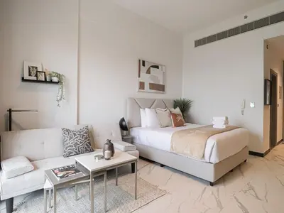 a living room with a bed and a couch at Welhome - Chic Studio with Balcony & City Views in Dubai in Dubai