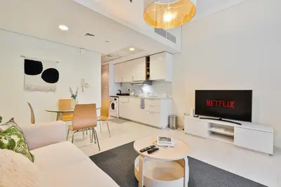 a living room with a couch and a tv and a table at Comfy Studio with Views Near Marina & Burj Al in Dubai