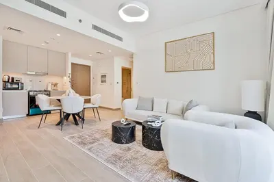 a living room with a white couch and a table at Vibrant 1BR With Airy Patio, Beach, Pool and Gym Access in Dubai