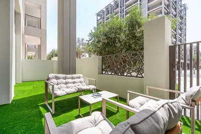 a patio with two chairs and a table on the grass at Vibrant 1BR With Airy Patio, Beach, Pool and Gym Access in Dubai