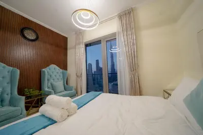 a bedroom with a large bed with two chairs and a window at Stunning 4BR Apartment with Full Burj Khalifa and Fountain View in Dubai