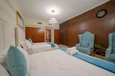 a hotel room with two beds and two blue chairs at Stunning 4BR Apartment with Full Burj Khalifa and Fountain View in Dubai