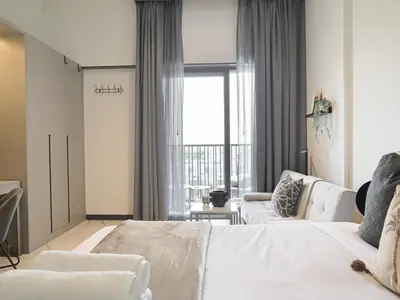 a bedroom with a large white bed and a couch at Welhome - Elegant Studio with Skyline Views & Comfort in Dubai