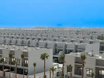 an aerial view of a large white apartment building with palm trees at Welhome - Elegant Studio with Skyline Views & Comfort in Dubai