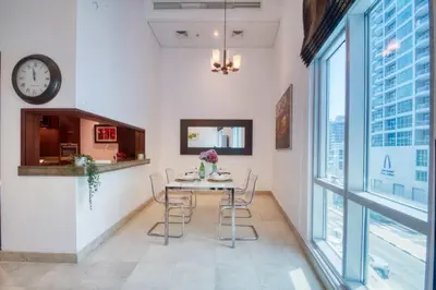 a dining room with a table and chairs and a clock at The Smart Concierge - Delphine in Dubai