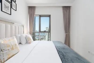 a bedroom with a white bed with a large window at Creek Side 18 I Harbor Views I in Dubai