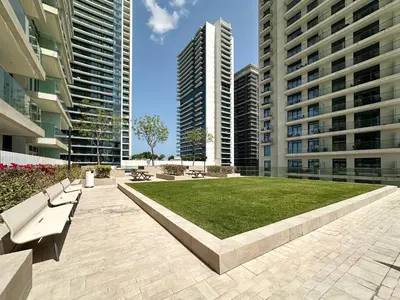 a park in the middle of two tall buildings at Trophy-Sunset Coral Retreat Beachfront Living in Dubai