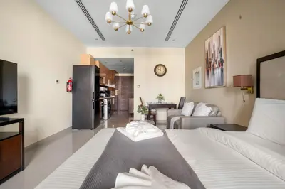 a bedroom with a bed and a living room at Stylish Downtown Studio in Dubai