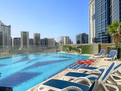 a large swimming pool with lounge chairs and a city skyline at Stylish Downtown Studio in Dubai