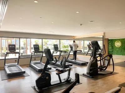 a man standing in a gym with several tread machines at Stylish Downtown Studio in Dubai
