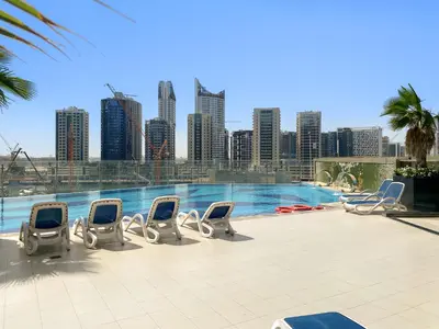 a swimming pool with chairs and a city skyline at Stylish Downtown Studio in Dubai