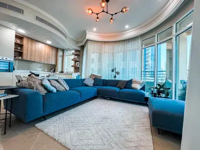 a living room with a blue couch and a kitchen at DreamShoma-Sea View 2BR Pool Gym in Dubai