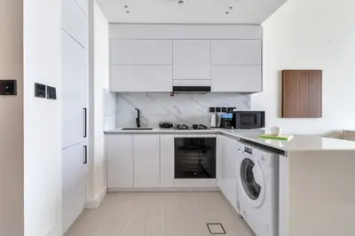 a kitchen with white cabinets and a washer and dryer at GuestReady - Charming haven in JVC in Dubai