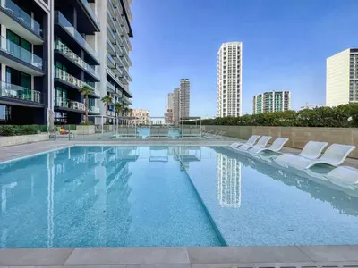 a swimming pool with white chairs and buildings at GuestReady - Charming haven in JVC in Dubai