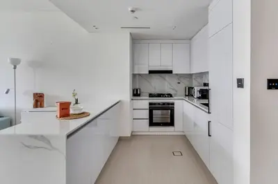 a white kitchen with white cabinets and appliances at GuestReady – Modern comfort in JVC in Dubai
