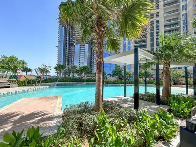 a swimming pool with palm trees and buildings at Sky High 1BR in City View with 41st Floor Views in Dubai