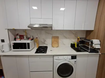 a kitchen with white cabinets and a washing machine at PANTHEON ELYSEE III Elite Apartment Spacious luxury stay with huge pool , modern gym and Complimentary welcome pack in Dubai