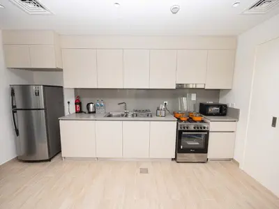a kitchen with white cabinets and a stainless steel refrigerator at Beach Access, Burj Khalifa View, Family Friendly in Dubai